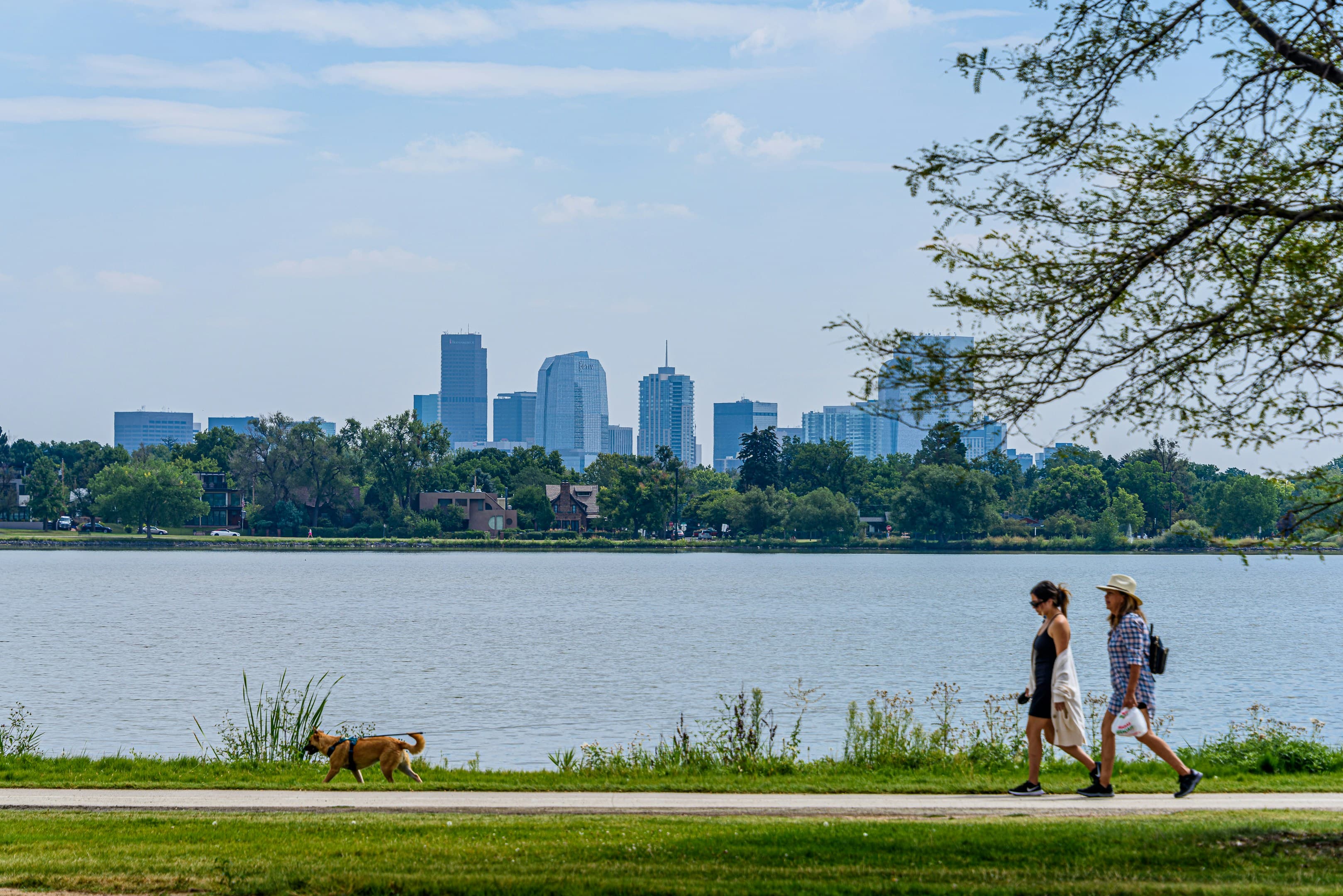 People walking beside Sloan's Lake with the Denver skyline across the water.